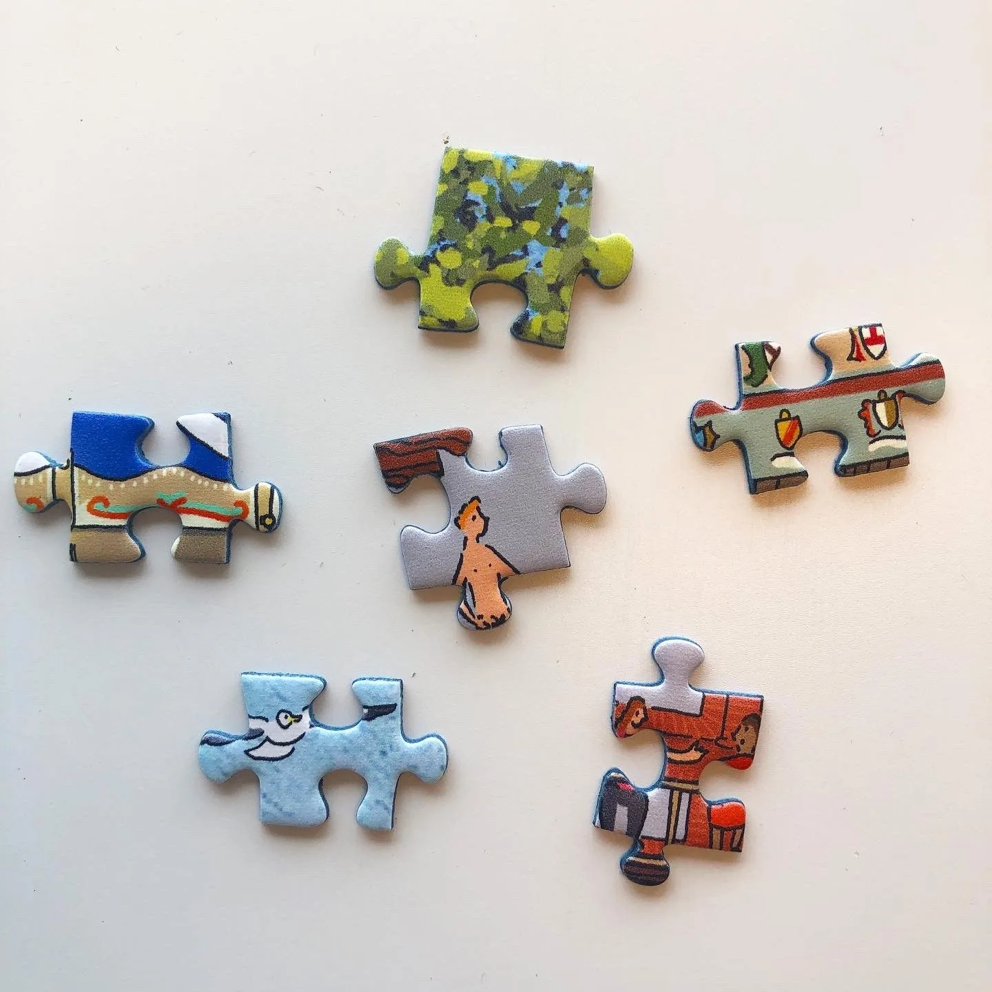 Zes losse puzzelstukjes met details uit Dwars door Amsterdam op een lichte tafel