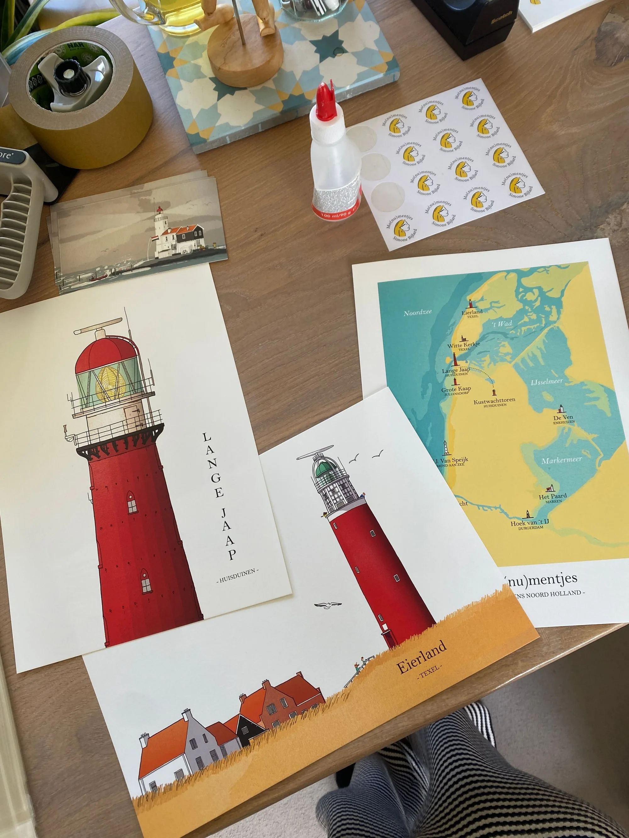 Prints van de vuurtorens Lange Jaap en Eierland en de kaart van Noord-Holland op de werktafel, naast een foto van de vuurtoren